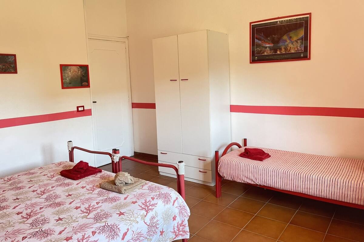 A room with two beds, a wardrobe, and a framed picture on the wall.