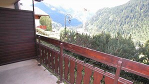 A balcony with a wooden railing overlooking a mountainous landscape.