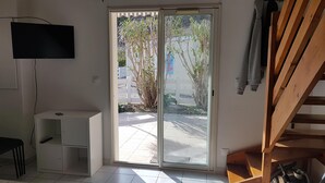 Une pièce dotée d’une porte-fenêtre coulissante donnant sur un espace extérieur, d’un meuble blanc et d’un escalier en bois.