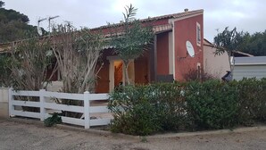 Un petit bâtiment à l’extérieur rouge, avec une clôture blanche devant.