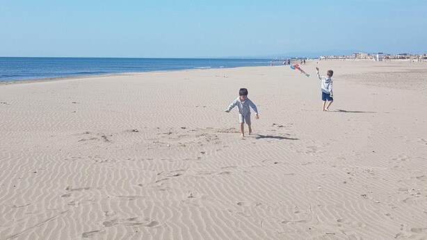 Une plage de sable avec des empreintes et un ciel bleu dégagé.