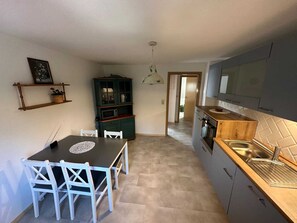 Une cuisine compacte avec un coin repas, un four à micro-ondes encastré et un plan de travail en bois.