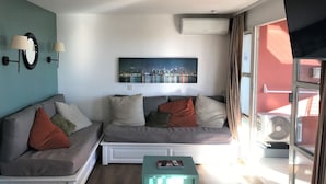 Ett modernt vardagsrum med en grå soffgrupp, ett soffbord och en tavla med en stadsbild på väggen.