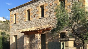 A stone building with a tiled roof and a gated entrance. - Our beautiful Greek home with private pool, large outdoor areas and lovely views (Stoupa)