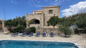 A stone building with a pool area, including lounge chairs and a clear blue pool. - Our beautiful Greek home with private pool, large outdoor areas and lovely views (Stoupa)