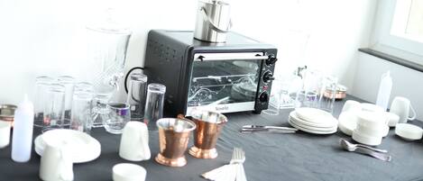 A table with a black tablecloth, a Novella toaster oven, and various glassware and dishes.
