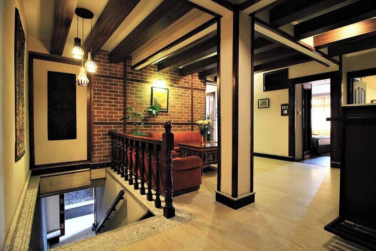 A spacious lobby with a staircase, a brick wall, and a red sofa.