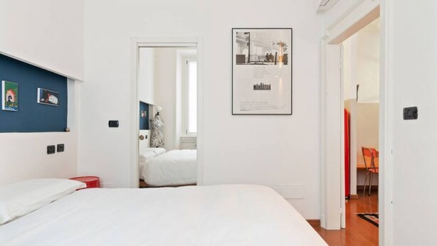 Un dormitorio con una cama, un cuadro en la pared y una puerta que da a otra habitación.
