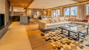 Un vaste espace de vie doté d’un plafond en bois, d’un grand canapé, d’une table basse et d’un mur en pierre.