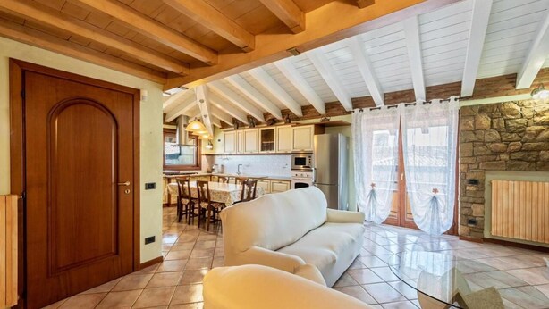 A spacious living area with a wooden ceiling, a stone wall, and a glass coffee table.