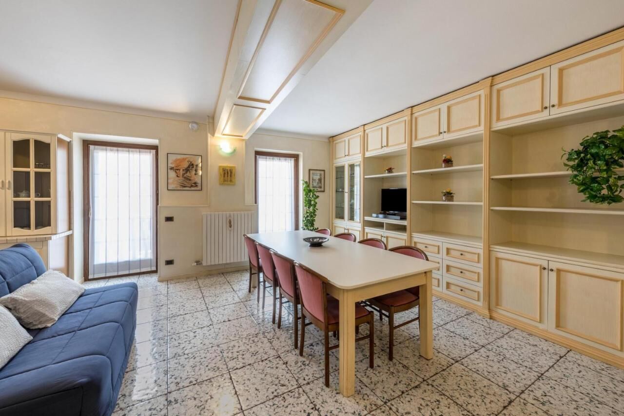 A dining area with a table and chairs, a blue sofa, and cabinets with shelves.