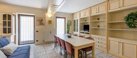 A dining area with a table and chairs, a blue sofa, and cabinets with shelves.