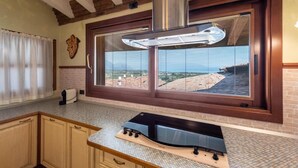 A kitchen with a large window, a built-in stove, and a view of rooftops.