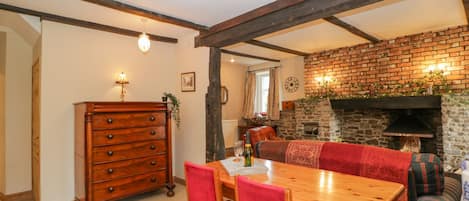 A dining area with a wooden table and chairs, a wooden dresser, and a brick fireplace.