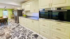 A modern kitchen with white cabinets, stainless steel appliances, and patterned floor tiles. - The Beach House Luxury Rooms (Weston-super-Mare)