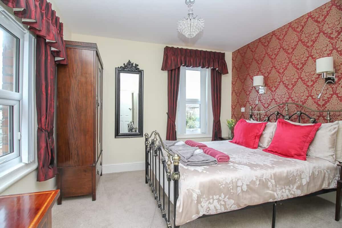 A bedroom with a bed, a wardrobe, a mirror, and a chandelier.