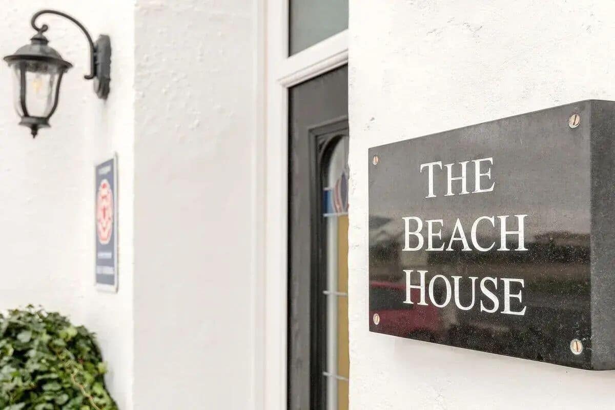 A sign that reads "The Beach House" mounted on a wall.