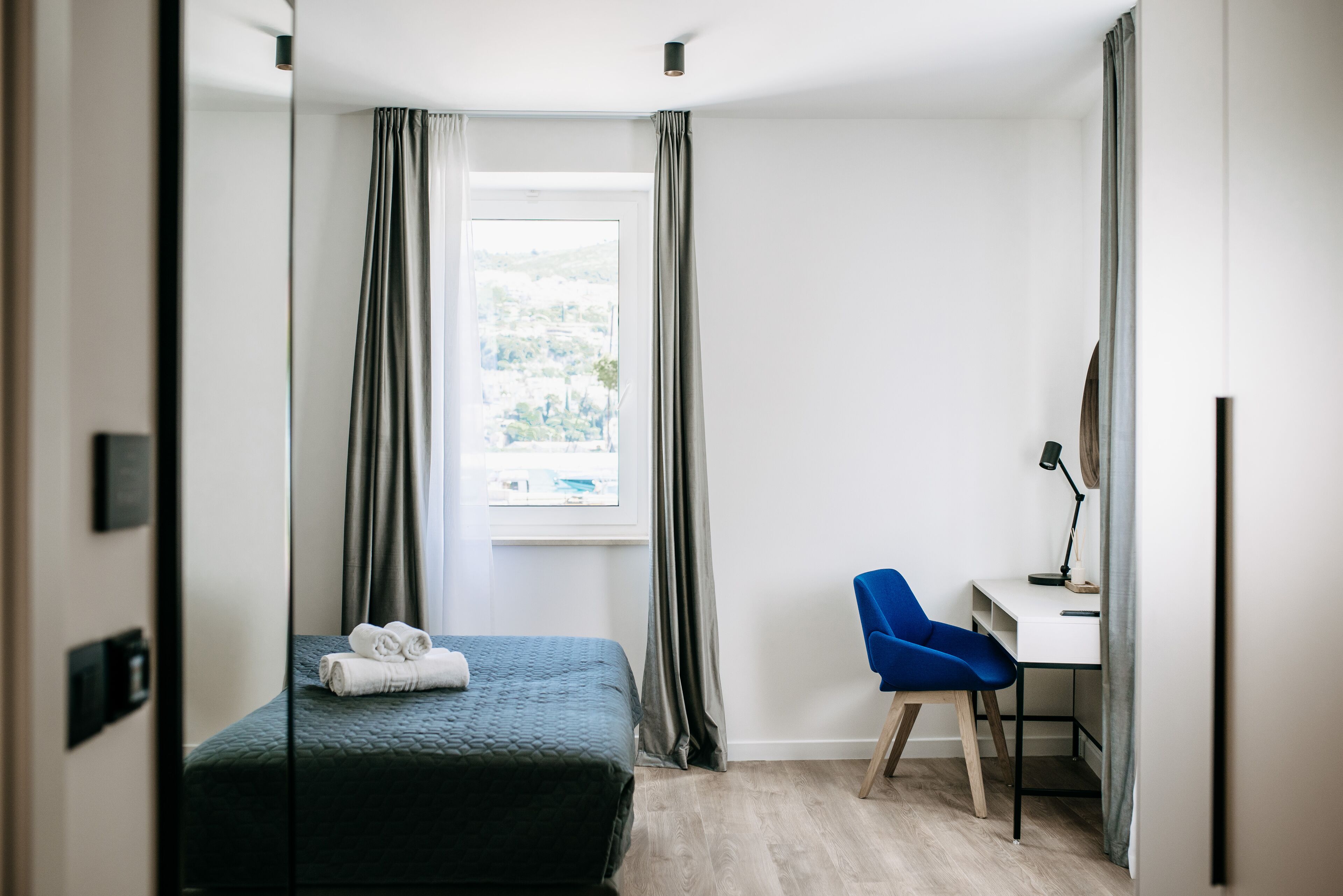 A bedroom with a bed, a desk, and a chair.