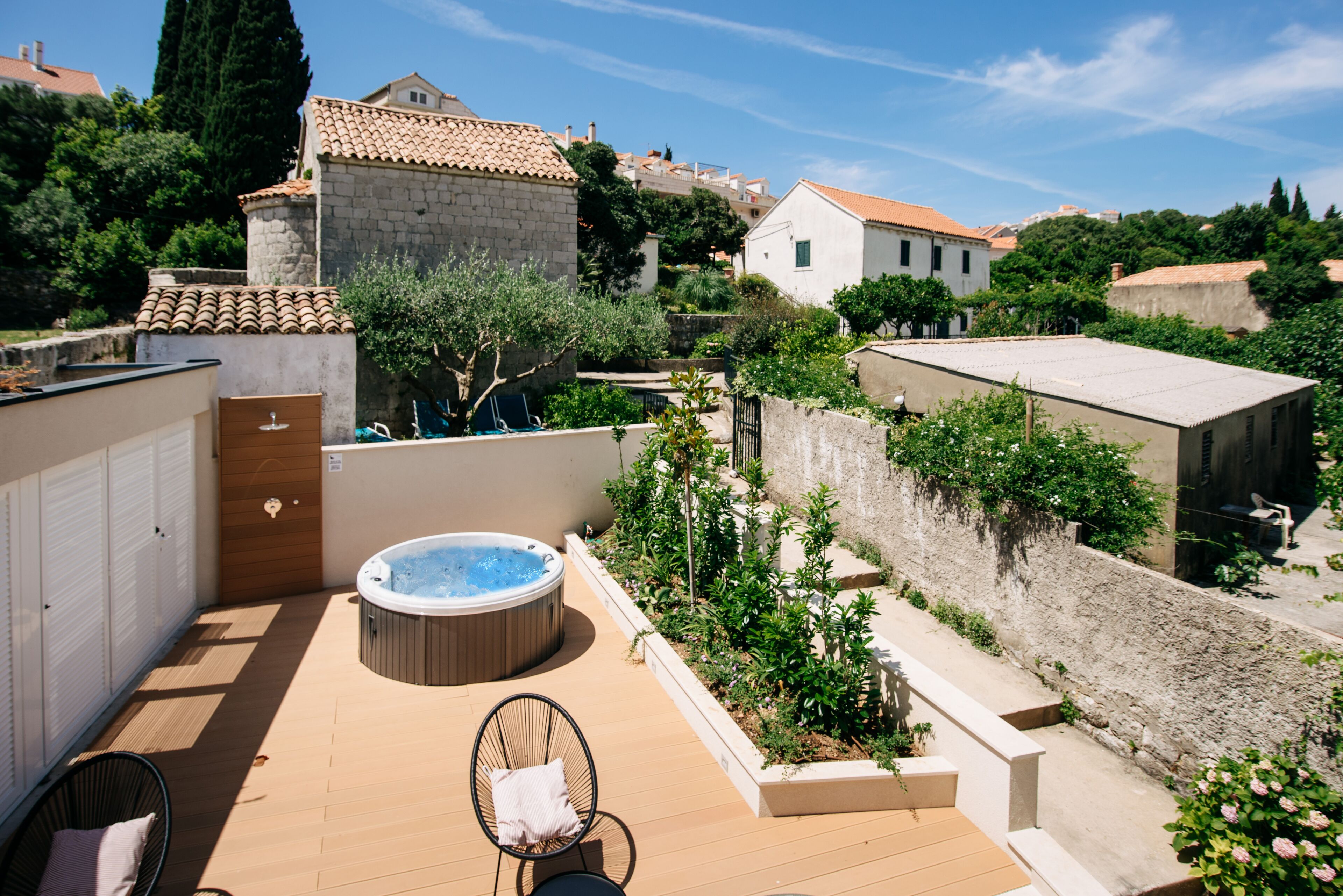 A rooftop terrace with a hot tub, seating area, and a view of surrounding buildings.