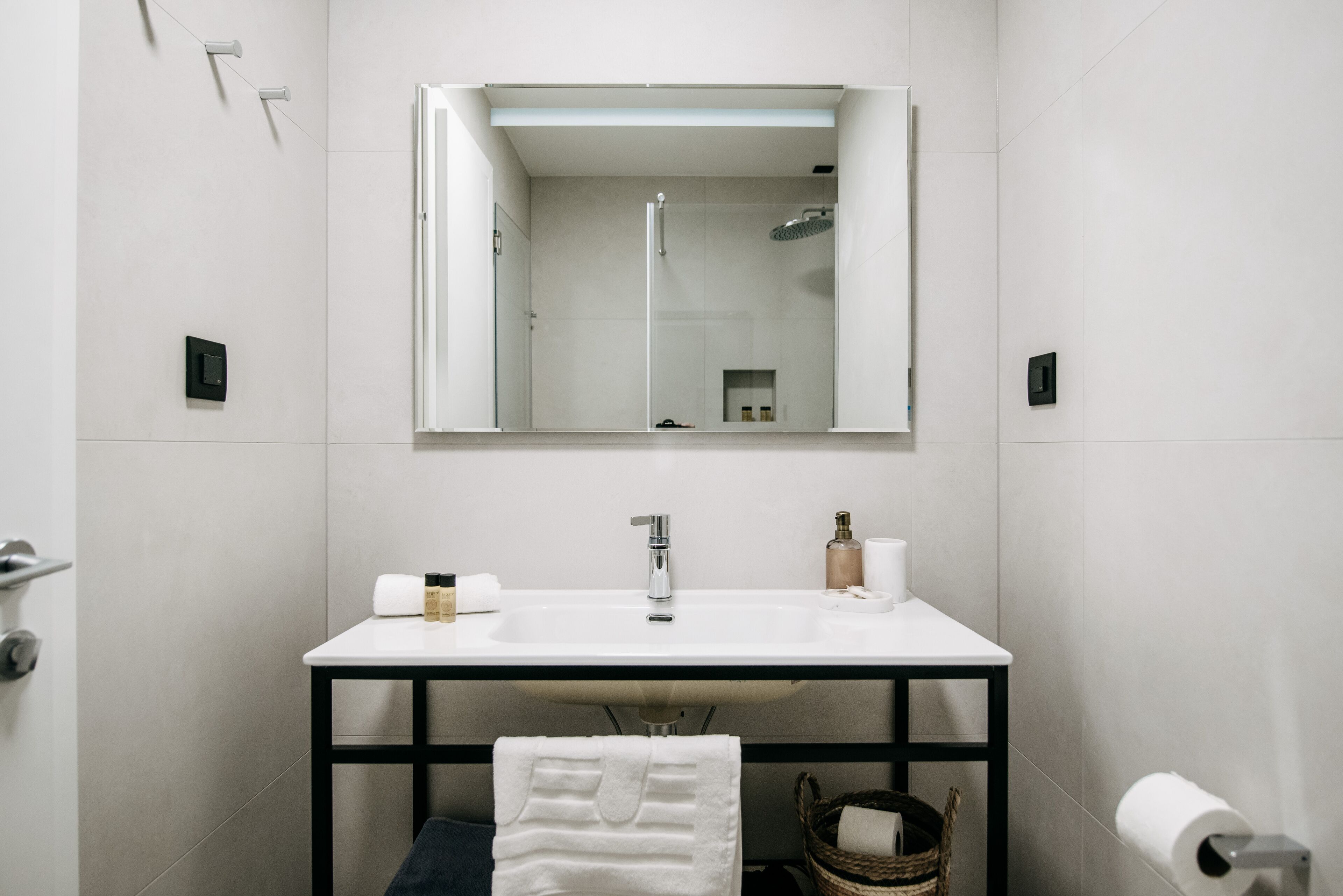 Un baño moderno con lavamanos, espejo y ducha blancos.