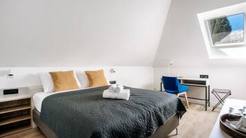 A modern bedroom with a large bed, a desk, and a chair.