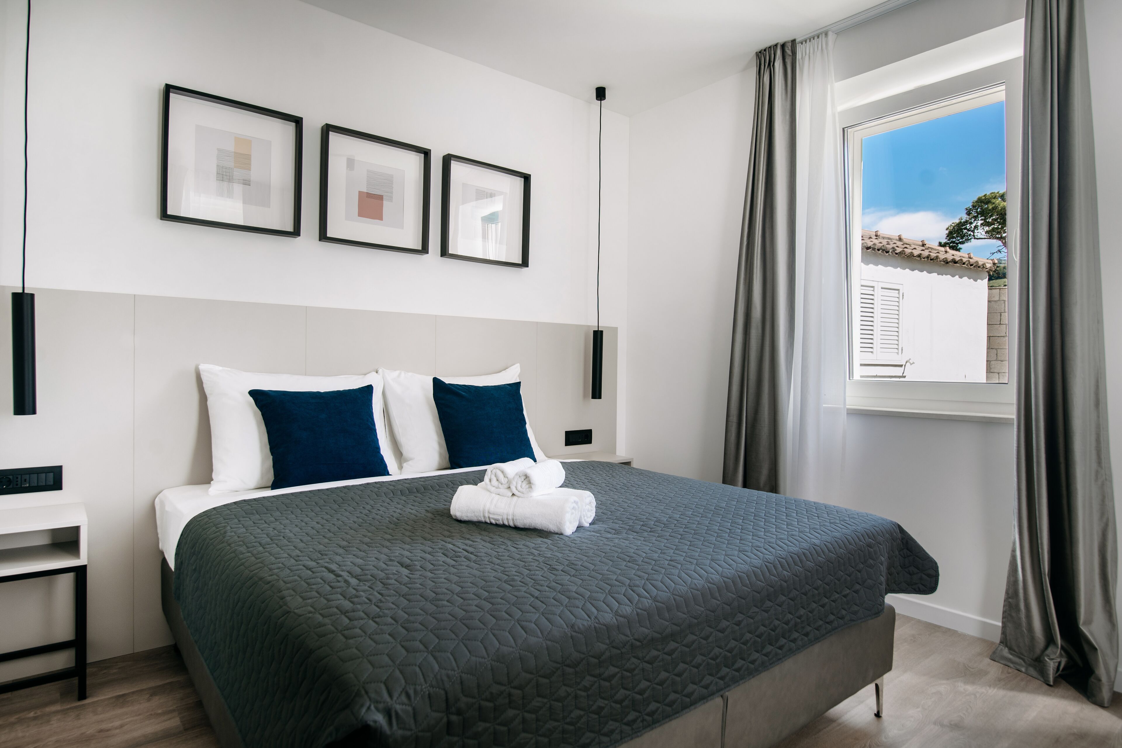 Une chambre d’hôtel moderne avec un grand lit, une table de chevet et une fenêtre avec des rideaux.