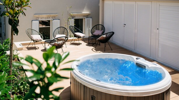A hot tub surrounded by outdoor seating and a garden.