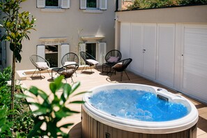Un bain à remous entouré d’un espace de détente extérieur et d’un jardin.