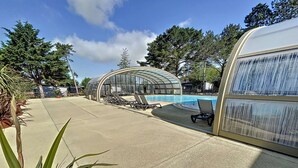 A pool area with lounge chairs and a glass-enclosed structure. - Cozy Chalet for 6 with Heated Pool, Terrace & Parking, Near Beach (Jullouville)