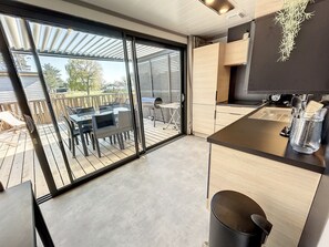 A modern kitchen with a sliding glass door leading to an outdoor patio area. - Cozy Chalet for 6 with Heated Pool, Terrace & Parking, Near Beach (Jullouville)