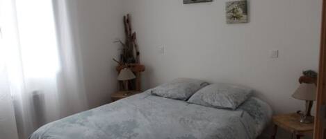 Un dormitorio con cama, mesita de noche, lámpara y un cuadro en la pared.