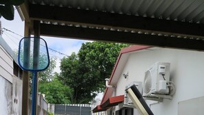 Ein schmaler Innenhof mit gefliestem Boden, einem roten Dach und einer an der Wand befestigten Klimaanlage.