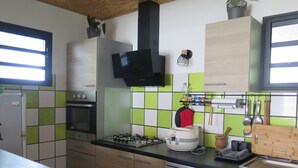 Eine moderne Küche mit Gaskochfeld, Backofen, Geschirrspüler und einer schwarzen Dunstabzugshaube.