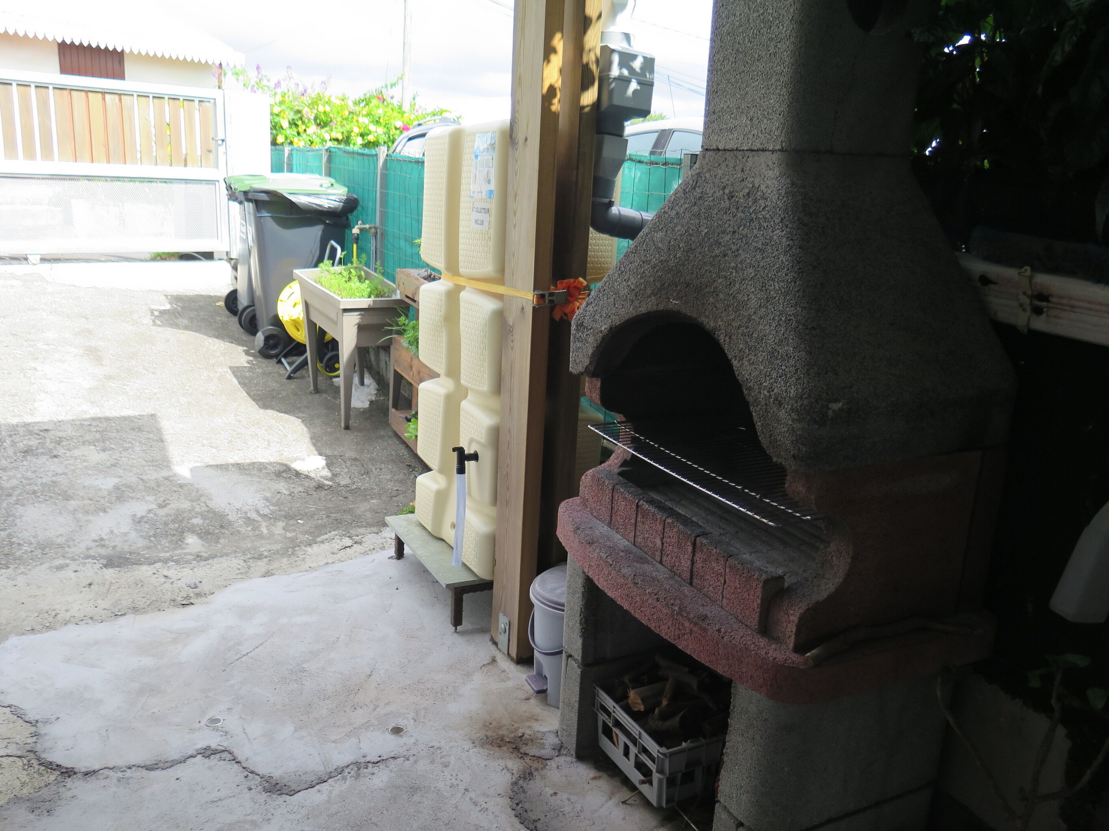 A stone-built outdoor oven, a concrete floor, and a wooden bench.