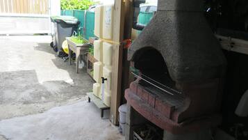 A stone-built outdoor oven, a concrete floor, and a wooden bench.
