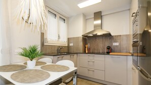 Eine moderne Küche mit einem weißen Tisch, grauen Schränken und einer Edelstahl-Dunstabzugshaube.