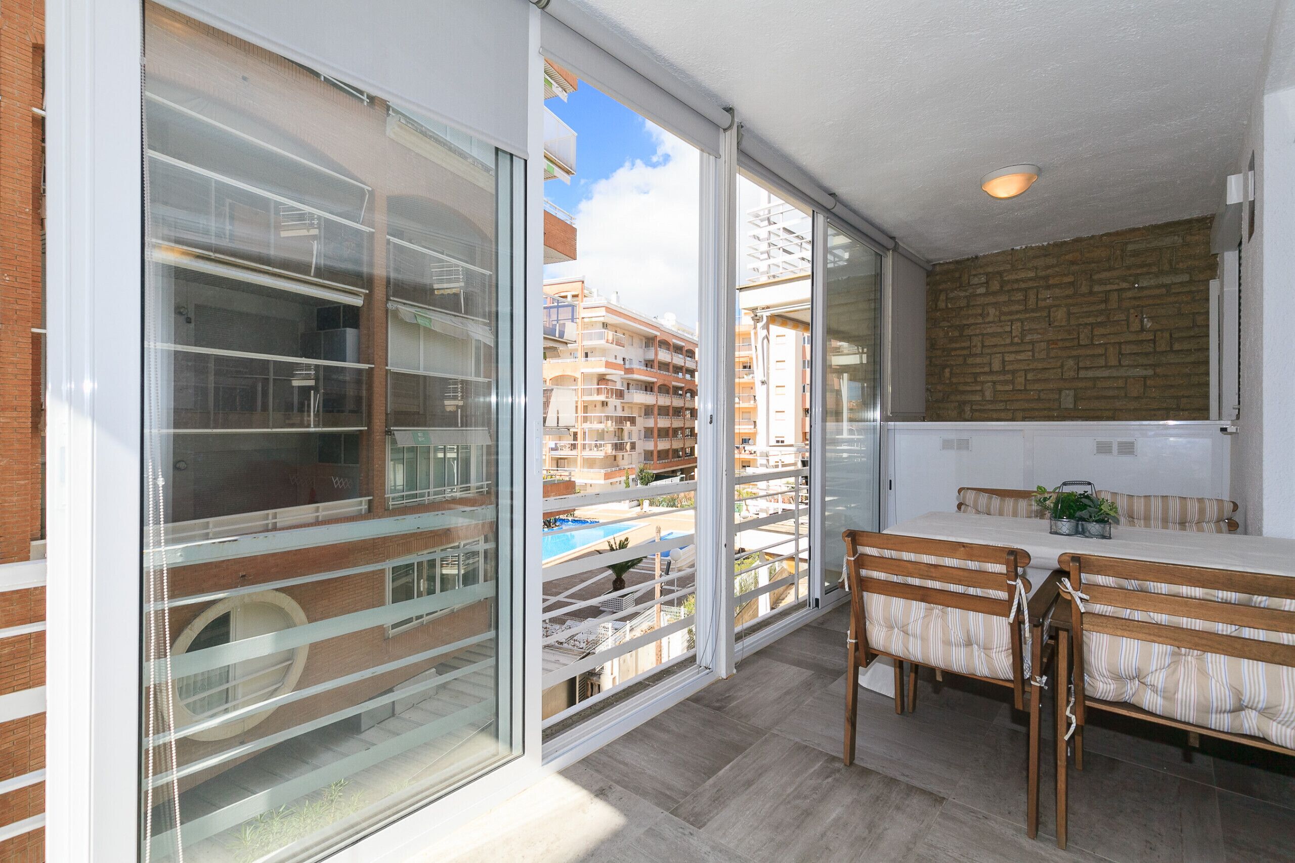 A balcony with a view of a swimming pool and adjacent buildings.