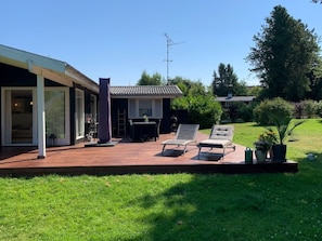 A modern house with a covered patio, a dining area, and a lawn.