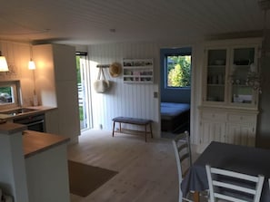 A cozy kitchen with a dining area, wooden flooring, and a view through a window.