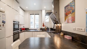 A modern kitchen with white cabinets, a dark countertop, and a large window. - Vivid, Vivace, by Veeve (Paris)