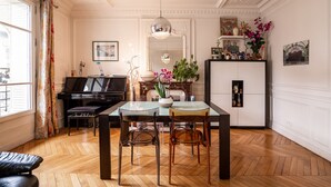 A dining area with a piano, a glass table, and chairs. - Vivid, Vivace, by Veeve (Paris)