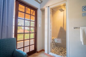 A room with a checkered shower floor, a blue chair, and a door leading to an outdoor area. - Kilima Private Game Reserve and Spa (Kareeberg)