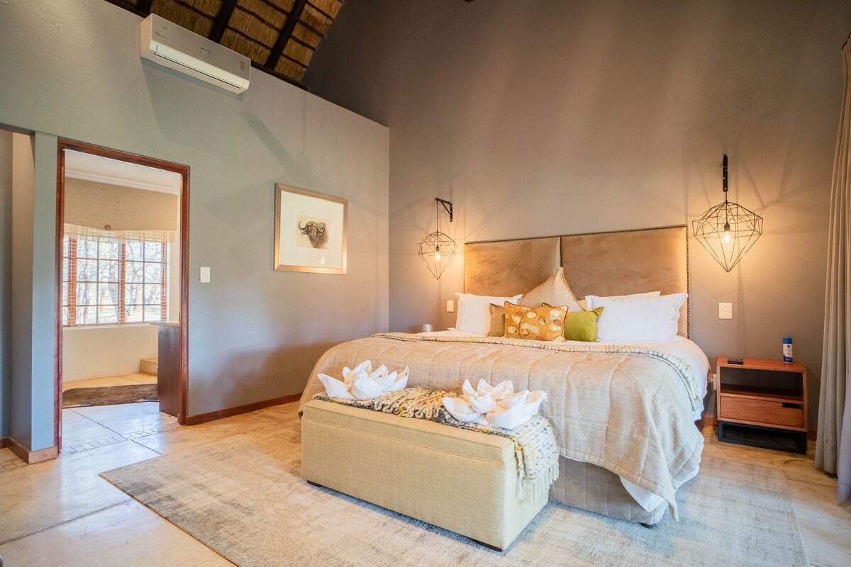 A bedroom with a bed, bedside tables, a nightstand, a window, and a door.