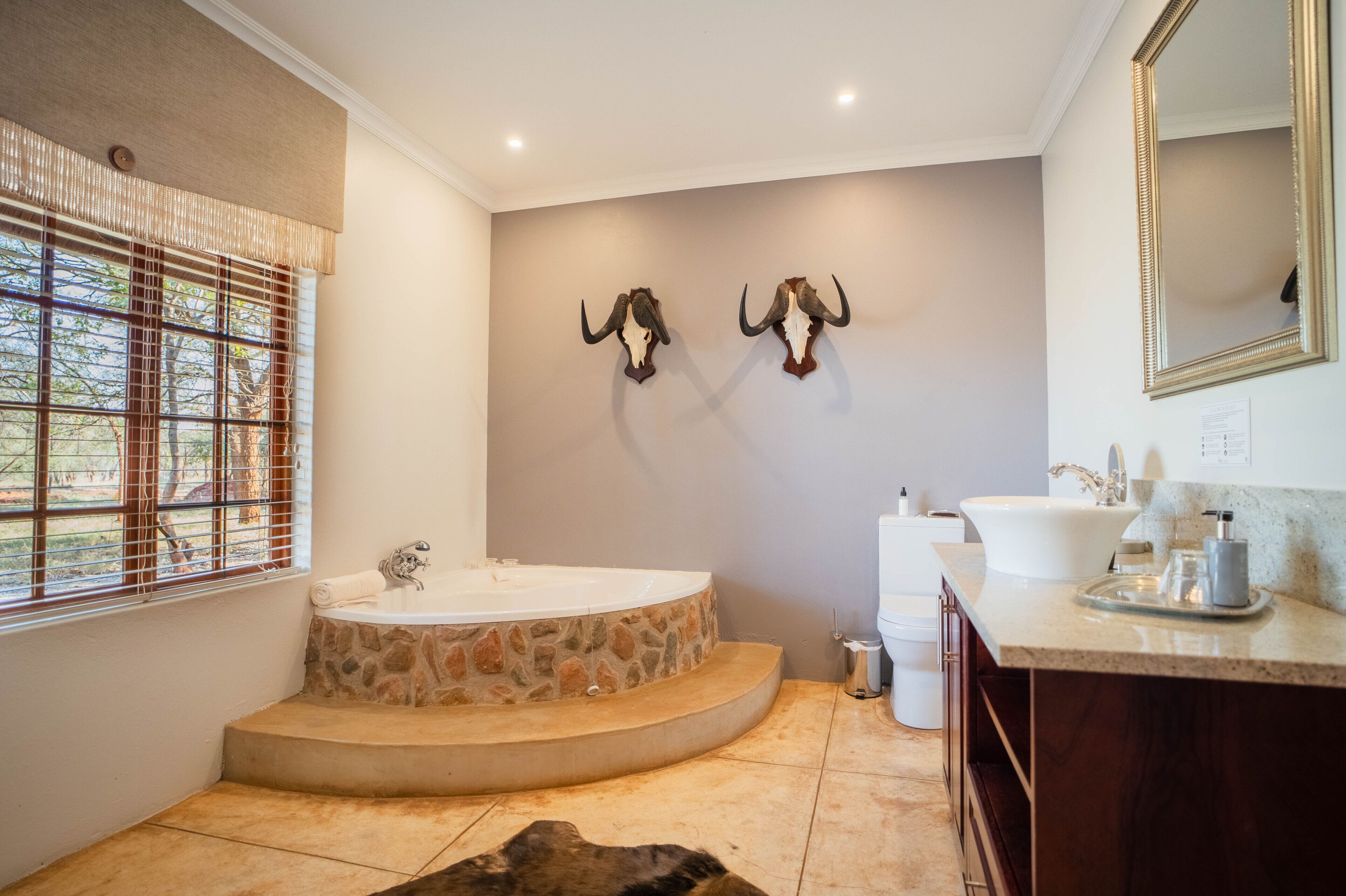 Un baño con una bañera de piedra, un lavamanos y dos cuernos montados en la pared.