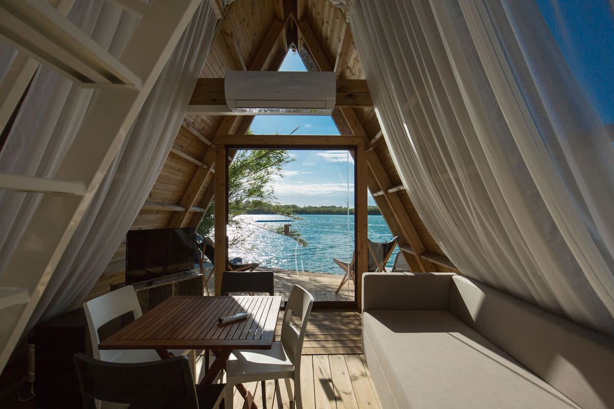 Une terrasse en bois avec une table et des chaises, un canapé et une vue sur un lac.