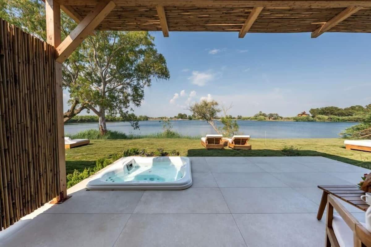 Un bain à remous situé dans un espace extérieur abrité, avec vue sur un lac et des arbres.