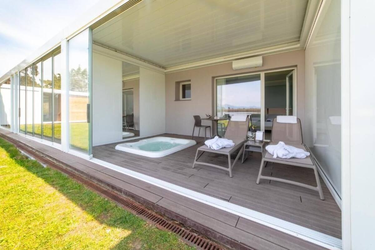 Un espace extérieur moderne doté d’un jacuzzi, de chaises longues et offrant une vue sur un lac.