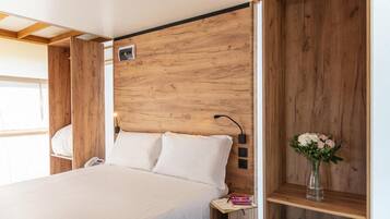 Un dormitorio con cabecera de madera, una mesita de noche con un teléfono y una pequeña estantería con un florero.