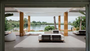 A modern outdoor lounge area with white furniture and a view of a lake.