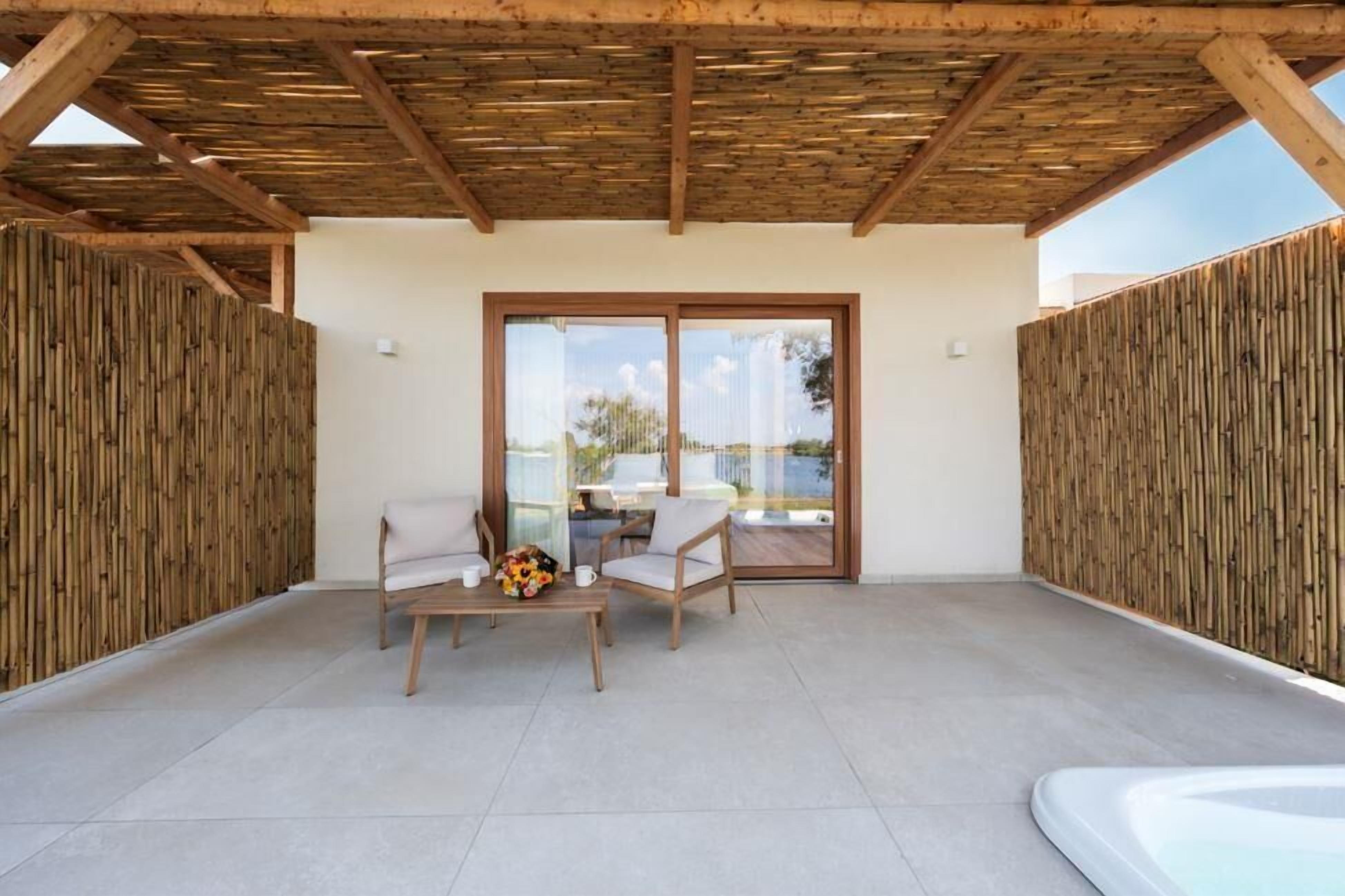 Un portico coperto con tavolo e sedie, una porta-vetro che dà sull'esterno e pareti in bambù.